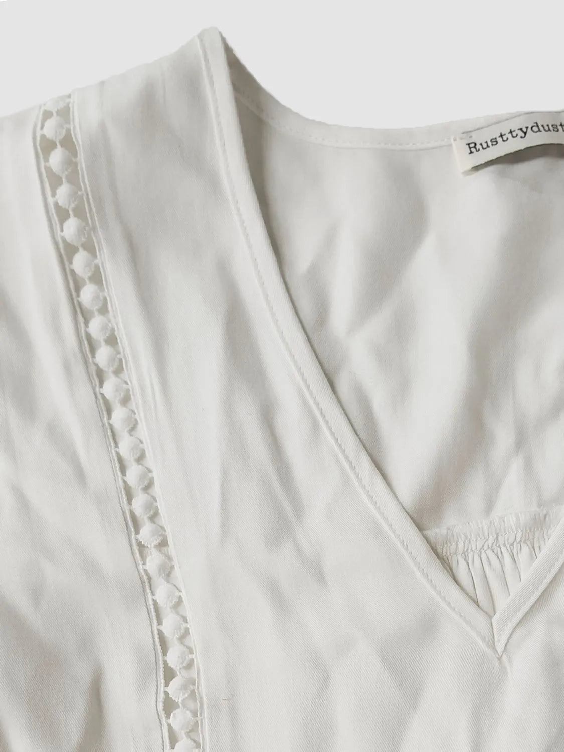 Close-up of white lace flounce sleeve blouse with V-neck, featuring delicate lace details and feminine cottage romance style.