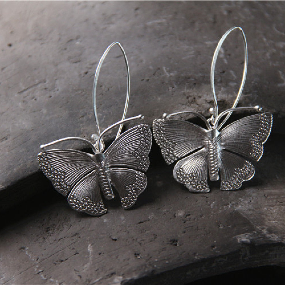 Sterling silver Moonshadow Moth earrings with French hook design, featuring intricate moth wing details and a delicate, artistic style.