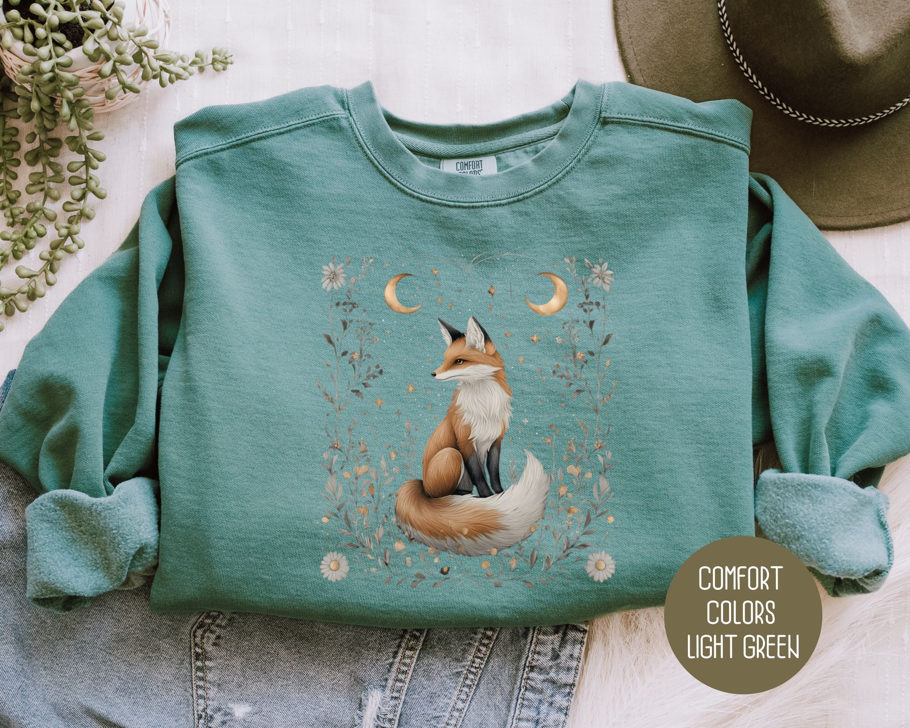 Light green Comfort Colors sweatshirt featuring a celestial fox design with starlit hollow details on the front.