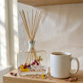 Woodland Bloom Botanical Reed Diffuser by Crazy About Candles, elegant glass bottle with decorative reeds and floral accents.