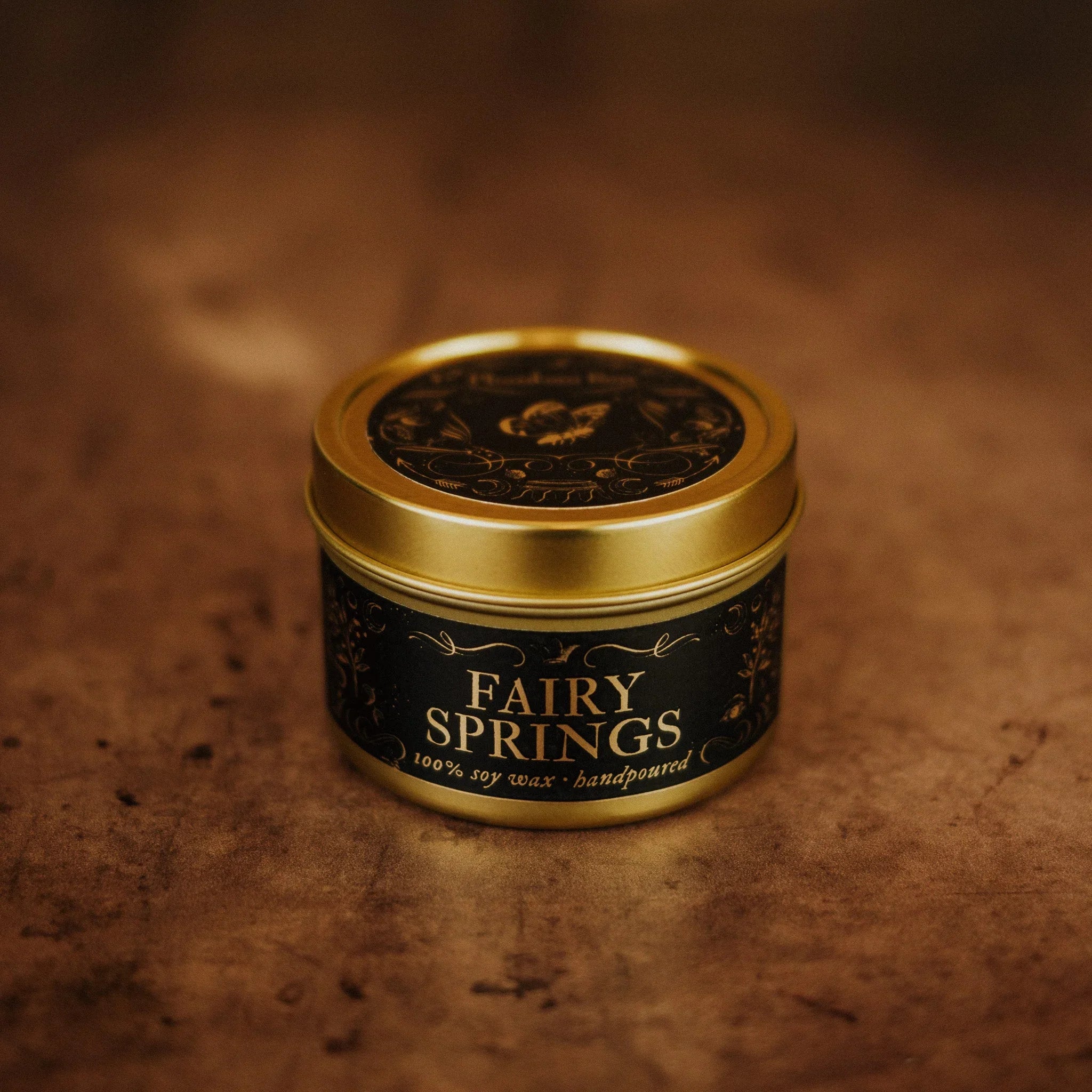 Phantom Row Fairy Springs candle in a decorative tin, featuring a whimsical fairy design and soft glowing light.