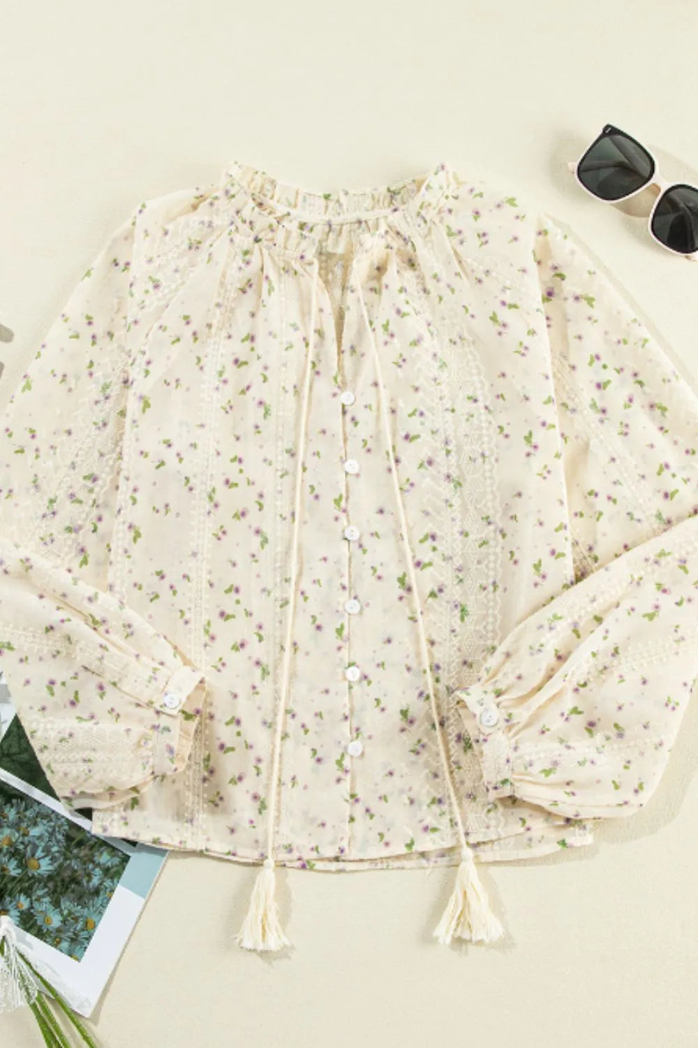 Flatlay of Meadow Lace and Frill Tie-Neck Blouse by Trendsi, featuring delicate lace details and a stylish tie-neck design.