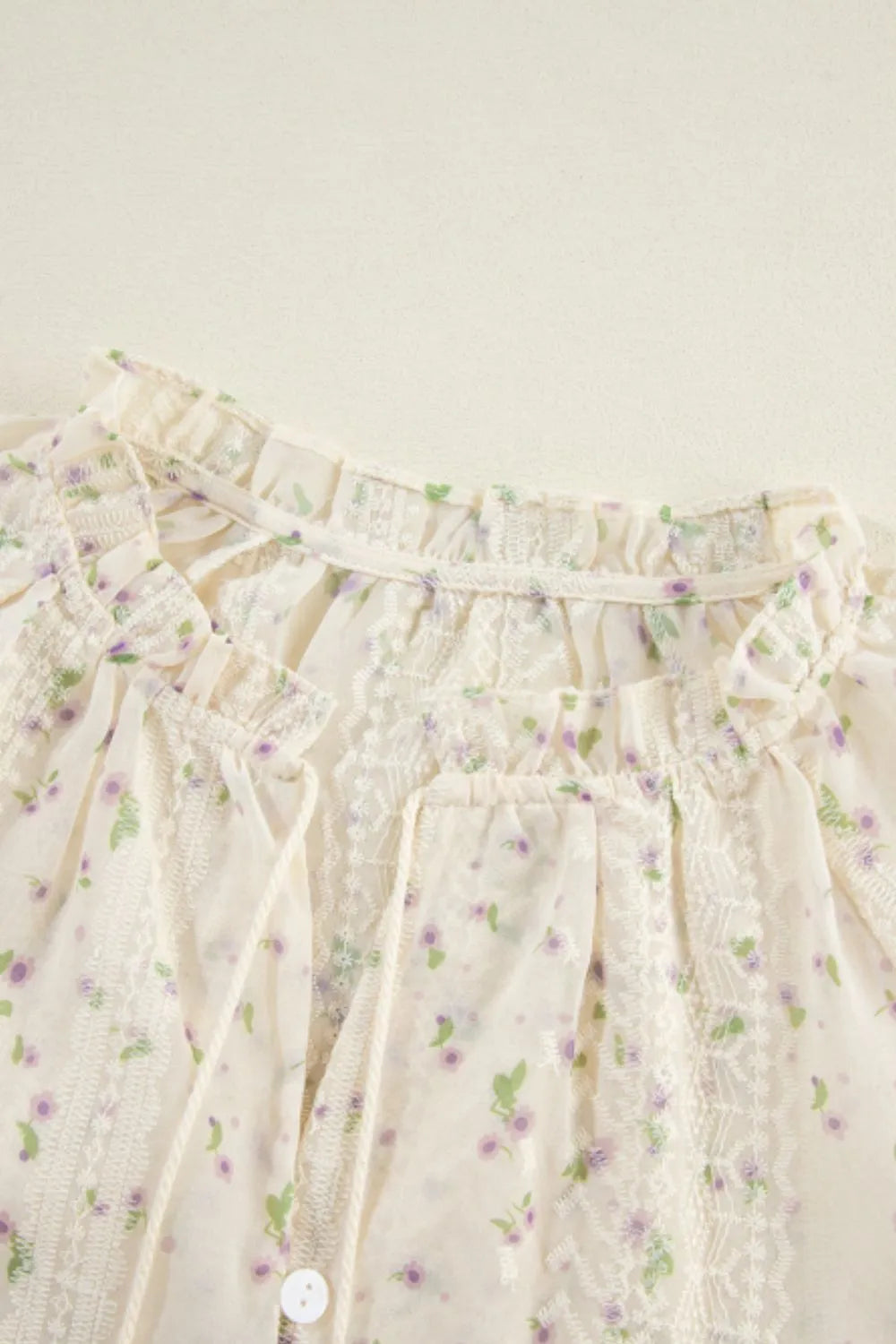Close-up of a Meadow Lace and Frill Tie-Neck Blouse showing intricate lace details and frill accents at the neckline.